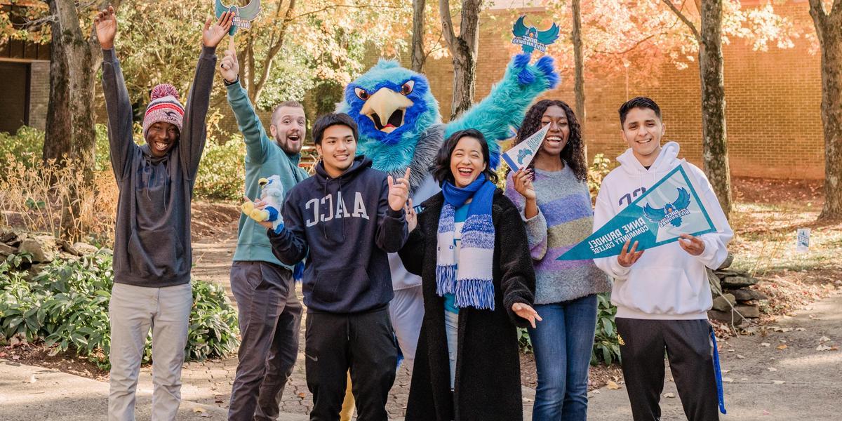 Students laughing and posing with AACC mascot, Swoop.